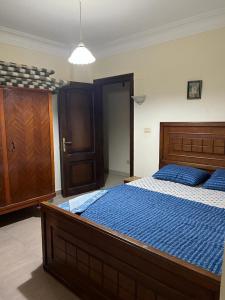 a bedroom with a large wooden bed with blue sheets at LA VISTA Ain Elsokhna 1&2 Chalet in Ain Sokhna