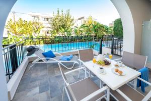 balcón con mesa, sillas y piscina en Peridis Family Resort en Cos