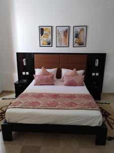 Djerba的住宿－HOTEL OLYMPIC DJERBA，卧室配有一张大床,墙上挂有四张照片