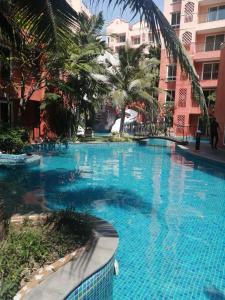 a large swimming pool with palm trees and buildings at Seven Seas Condo Resort Beautiful Location in Jomtien Beach