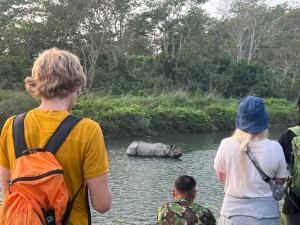 um grupo de pessoas olhando para um rinoceronte em um rio em Chitwan Park Village em Sauraha