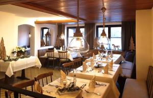 un restaurante con mesas y sillas blancas y ventanas en Gasthof Hirsch, en Schollbrunn