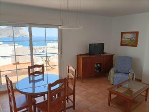 een woonkamer met een tafel en stoelen en een televisie bij Apartahotel Vistamar San José in San José