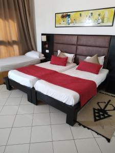 HOTEL OLYMPIC DJERBA في Djerba: سرير كبير مع وسائد حمراء في الغرفة