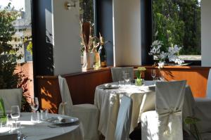 una sala da pranzo con tavoli e sedie bianchi e finestre di Hotel Cinzia Ristorante Christian e Manuel a Vercelli