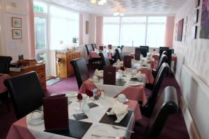 a dining room with tables and chairs with red tablecloths at The Swiss Cottage, Shanklin in Shanklin