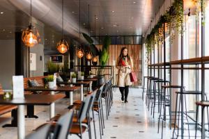 a woman walking through a restaurant with tables and chairs at Cabinn City in Copenhagen
