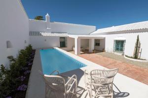 Casa blanca con piscina y sillas en CORTIJO LA MINA - Luxury Villa Conil, en Conil de la Frontera
