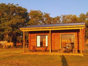 a small log cabin with two chairs and a table at Cabañas El Encuentro Lobos in Salvador María