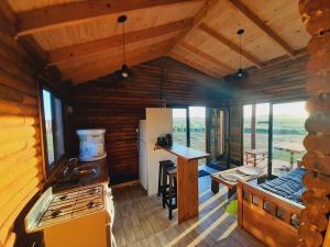 a kitchen in a log cabin with a stove and a counter at Cabañas El Encuentro Lobos in Salvador María