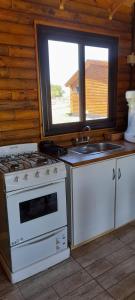 uma cozinha com um fogão, um lavatório e uma janela em Cabañas El Encuentro Lobos em Salvador María
