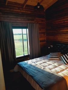 Schlafzimmer mit einem großen Bett und einem Fenster in der Unterkunft Cabañas El Encuentro Lobos in Salvador María