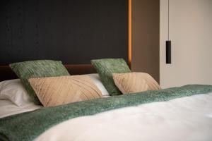 uma cama branca com duas almofadas e lençóis verdes em Yzerdyck em Diksmuide