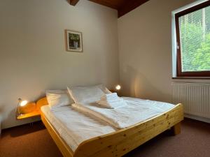 a bedroom with a bed with white sheets and a window at Apartmány DOKY Holiday in Lipno nad Vltavou +19 photos