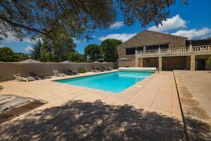 una piscina con sillas y una casa en Château de Floure - Hôtel, restaurant, SPA et piscine extérieure chauffée en Floure