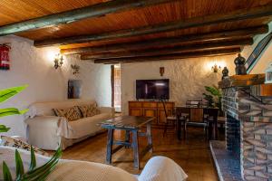 a living room with a couch and a table and a tv at Casa Rural El Majano in Moya