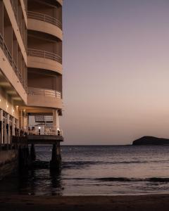 a building on the beach next to the ocean at Hotel M&eacute;dano in El M&eacute;dano