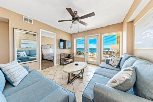 a living room with a blue couch and a ceiling fan at Boardwalk Building Sunset Corner Condo in Gulf Shores