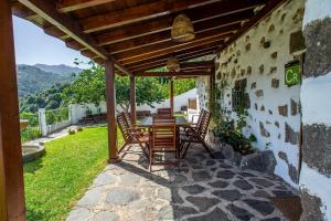 a patio with a table and chairs under a wooden roof at Casa Rural El Majano in Moya