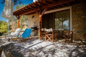un patio con sillas, una mesa y una casa en Beautiful Traditional Stone House in the private Sea Front Olive Grove of Elaionas Nikou Luxury Villas, en Alyfantá