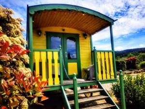 a small yellow and green house with a porch at Roulotte de la Villa Font Vive - Tout équipée, tout confort, situation idéale Sud Ardèche in Grospierres