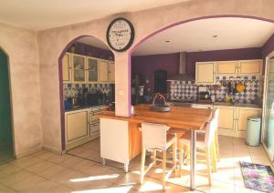 cocina con mesa y reloj en la pared en Villa Mistral - Profitez du calme de l'Ardèche -, 