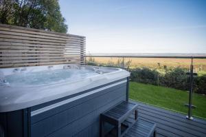 a bath tub on a deck with a view of a field at The Rhossili Bay Secret - 1 Bed Cabin - Landimore in Gowerton