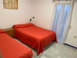 1 dormitorio con 2 camas con sábanas rojas y ventana en Apartamento Medina Puerto Sherry, en El Puerto de Santa María