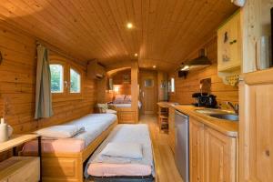 a small kitchen with a bed in a log cabin at Roulotte de la Villa Font Vive - Tout équipée, tout confort, situation idéale Sud Ardèche in Grospierres