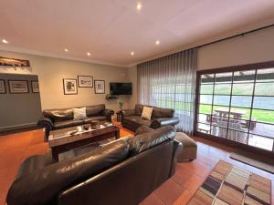 a living room with leather furniture and a large window at Le Rendezvous in Dullstroom