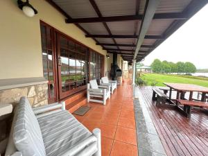 a porch with white benches and tables on a house at Le Rendezvous in Dullstroom