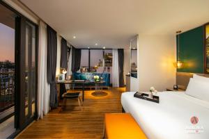 a hotel room with a bed and a living room at Aurora Premium - A Lifestyle Hotel in Hanoi