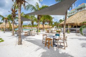 una playa con mesas, sillas y palmeras en Blue Bay Exclusive - 66, en Dorp Sint Michiel