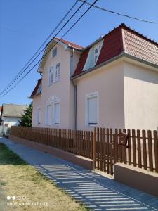 une maison blanche avec une clôture en bois dans l'établissement Villa Napsugár, à Balatonlelle