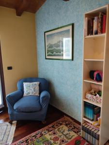 einen blauen Stuhl in einem Zimmer mit Bücherregal in der Unterkunft Lovely Casa Paola in Villafranca di Verona