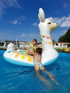 a boy and a child on an inflatable giraffe in the water at Hoya Glamping in Gostynin