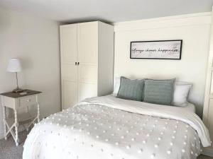 a white bedroom with a bed and a night stand at The Bruce Beach House - Cozy cottage by the lake! in Moraviantown