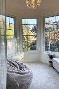 a bedroom with windows and a bed and a chandelier at The Bruce Beach House - Cozy cottage by the lake! in Moraviantown