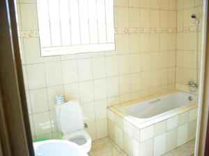 y baño con bañera, aseo y lavamanos. en Room in BB - Martin Aviator Hotel en Kigali