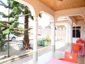 a porch with a palm tree and orange chairs at Room in BB - Martin Aviator Hotel in Kigali