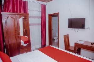 a bedroom with a bed and a desk and a television at Room in BB - Martin Aviator Hotel in Kigali