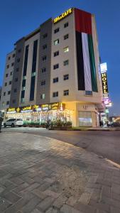 Onyx Hotel Apartments - MAHA HOSPITALITY GROUP في عجمان: مبنى كبير عليه علم