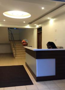 a woman sitting at a counter in a lobby at Hellenis Guest House in Kakamega