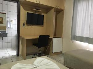 um quarto com uma secretária, uma cadeira e uma televisão em Hotel Paris em Curitibanos