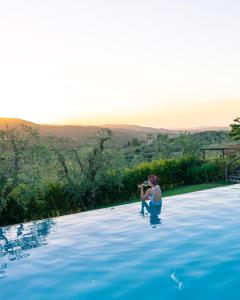 uma mulher sentada à beira de uma piscina em Casolese di Vignamaggio em Greve in Chianti