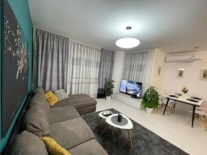 ein Wohnzimmer mit einem Sofa und einem TV in der Unterkunft Modern Apartment at Train Station in Tirana