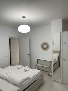 ein weißes Schlafzimmer mit einem Bett und einem Spiegel in der Unterkunft Modern Apartment at Train Station in Tirana