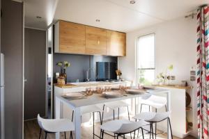 a kitchen with a white island with white chairs at Camping Le Sainte Marie in Sainte-Marie-la-Mer