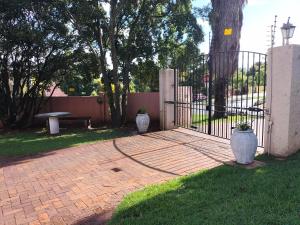 a wrought iron gate with two white vases on a brick patio at The Terrace Guest House in Roodepoort