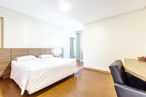 um quarto com uma cama branca e um sofá preto em Porto Minas Hotel e Convenções em Uberlândia